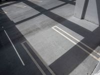 parking garage area with empty white lines on concrete flooring and walls with a car parked in background