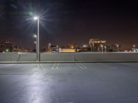 empty parking lot with city lights over the city skyline in the background at night time