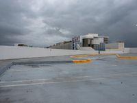 a parking lot with concrete walls with cars parked on the curb and a building in the background