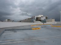 a parking lot with concrete walls with cars parked on the curb and a building in the background