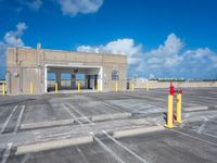 an empty parking lot with yellow poles and red fire hydrant at the end of the walkway