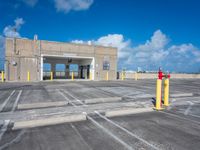 an empty parking lot with yellow poles and red fire hydrant at the end of the walkway