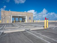 an empty parking lot with yellow poles and red fire hydrant at the end of the walkway