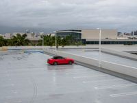 a red sports car in an empty parking lot area next to buildings in the background