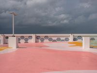 an empty parking lot next to the ocean, with a red floor and pink and yellow painted floors