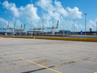 an empty parking lot filled with lots of buildings and trucks in the background of a cloudy blue sky