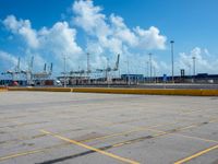 an empty parking lot filled with lots of buildings and trucks in the background of a cloudy blue sky