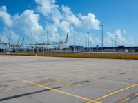 an empty parking lot filled with lots of buildings and trucks in the background of a cloudy blue sky