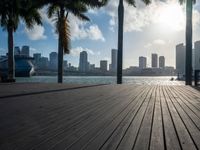 the view of a city in the sun with some palm trees next to the boardwalk