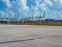 an empty parking lot filled with lots of buildings and trucks in the background of a cloudy blue sky