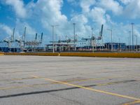 an empty parking lot filled with lots of buildings and trucks in the background of a cloudy blue sky