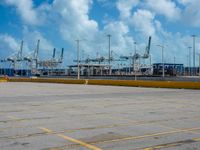 an empty parking lot filled with lots of buildings and trucks in the background of a cloudy blue sky