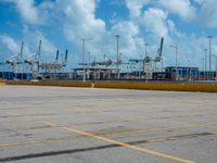 an empty parking lot filled with lots of buildings and trucks in the background of a cloudy blue sky