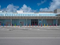 an empty parking lot is pictured under a clear blue sky with white clouds above it