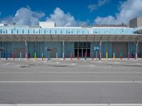 an empty parking lot is pictured under a clear blue sky with white clouds above it