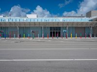 an empty parking lot is pictured under a clear blue sky with white clouds above it