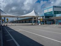 a bus stop with an awning is at the airport terminal and a blue and green building