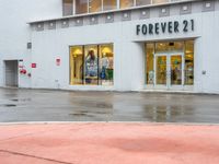 a shopfront with rain on the ground and sign above a store window that says forever 21