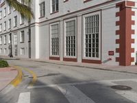 a large building is painted white and red on the street side and has an intersection