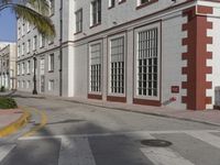 a large building is painted white and red on the street side and has an intersection