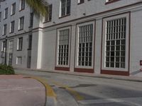 a large building is painted white and red on the street side and has an intersection