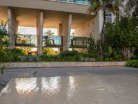 a skateboarder rides through a puddle in front of a tall building with palm trees