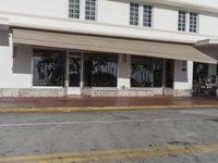 an empty commercial building in a city street next to a red fire hydrant with a tree and beach