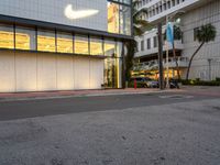 the exterior of a business building is lit up in yellow and purple light in the dusk