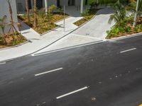 an empty street is next to two small parking spaces in front of some buildings and palm trees