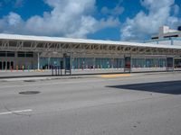 a bus station on a road with cars driving around it and a blue sky behind