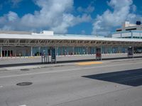 a bus station on a road with cars driving around it and a blue sky behind