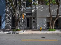 a building with some trees and a yellow fire hydrant on it's side