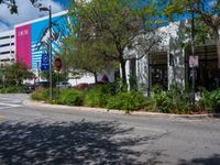 an empty street with a building on the side and traffic light next to it under some trees