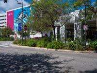 an empty street with a building on the side and traffic light next to it under some trees