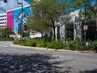 an empty street with a building on the side and traffic light next to it under some trees