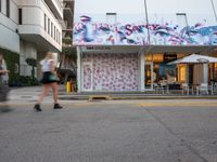 a car is passing a large building with graffiti on it's side, on the street