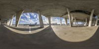 a photo looking in from the floor at an empty skate park or skating court with concrete columns and pillars