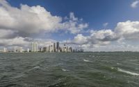 a view of a large city on the ocean and buildings on a cloudy day from the water