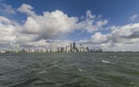 a view of a large city on the ocean and buildings on a cloudy day from the water