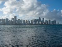 a city skyline seen from the water with a few boats in it at anchor in a body of water