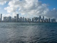 a city skyline seen from the water with a few boats in it at anchor in a body of water