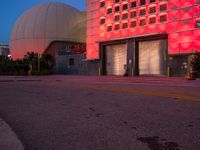 there are multiple types of buildings lit up at night in the day time with red lighting and an orange hue