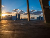 a city skyline is in the distance as the sun sets over the buildings that overlook the beach