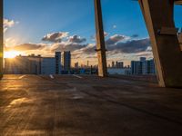 a city skyline is in the distance as the sun sets over the buildings that overlook the beach