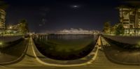 a view of a body of water with a moon in the background with buildings near by