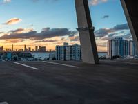 a man on a skateboard in an urban setting, with the sun setting over the city