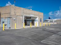 an empty parking lot on the roof of an industrial building with yellow columns surrounding the entrance