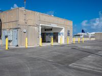 an empty parking lot on the roof of an industrial building with yellow columns surrounding the entrance