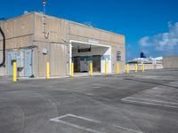 an empty parking lot on the roof of an industrial building with yellow columns surrounding the entrance