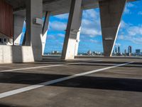 an empty parking garage with multiple columns on one side and sky scrapes behind it